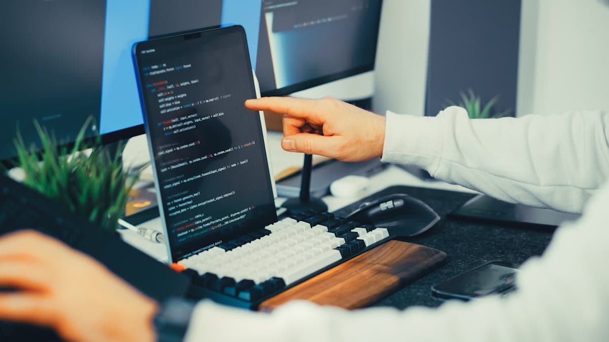 Developer trabajando en automatización de workflows con portátil y monitor
